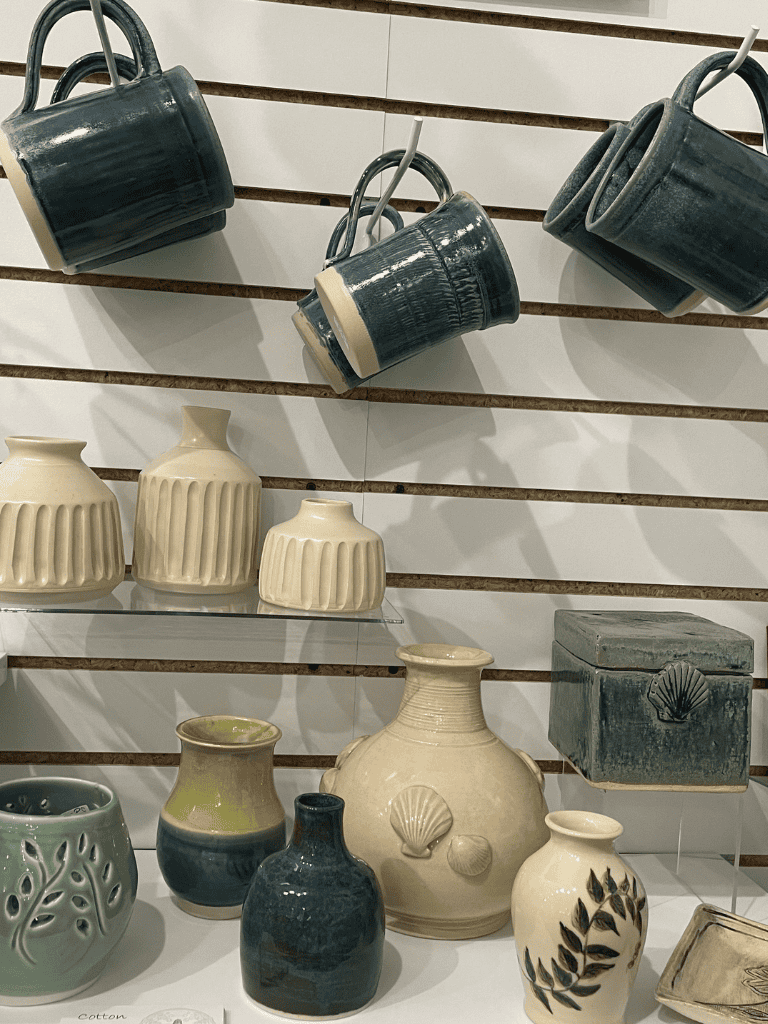 Stylish ceramic mugs hanging and decorative vases display in home decor shop.