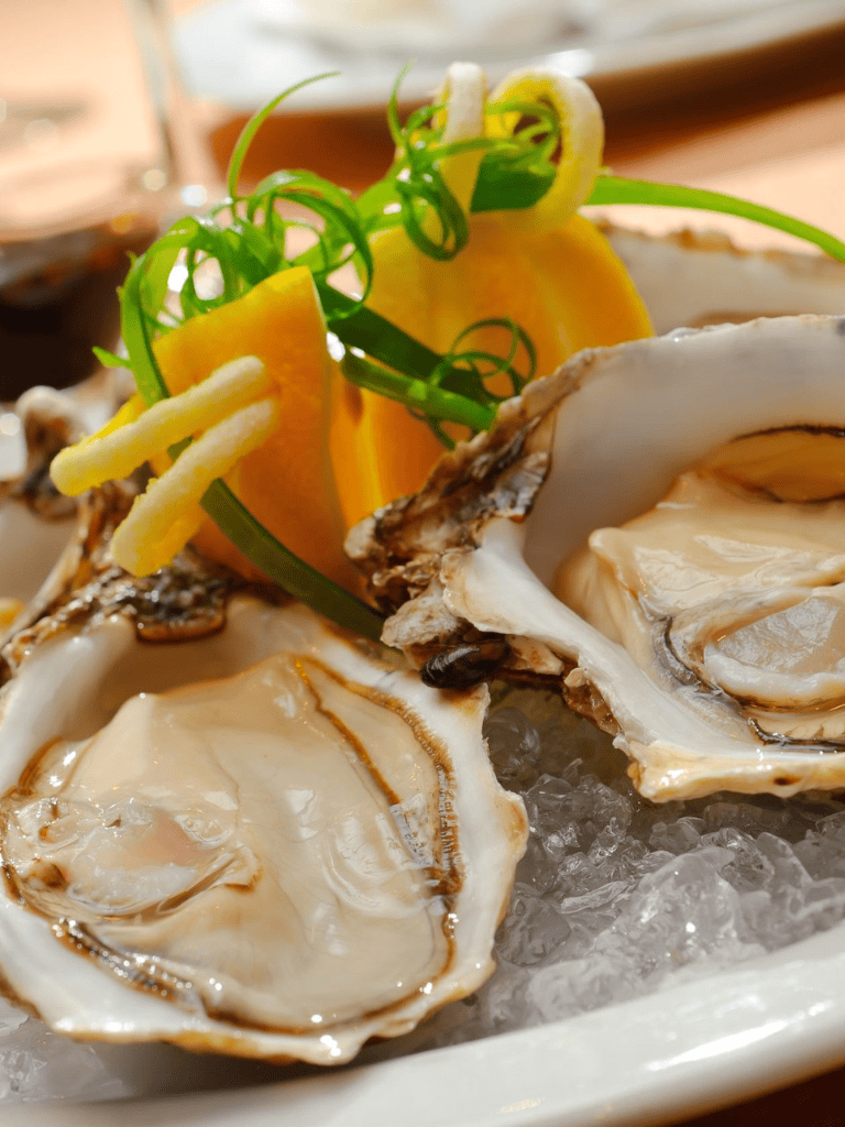 Fresh oysters on ice with lemon and green garnishes for seafood lovers.