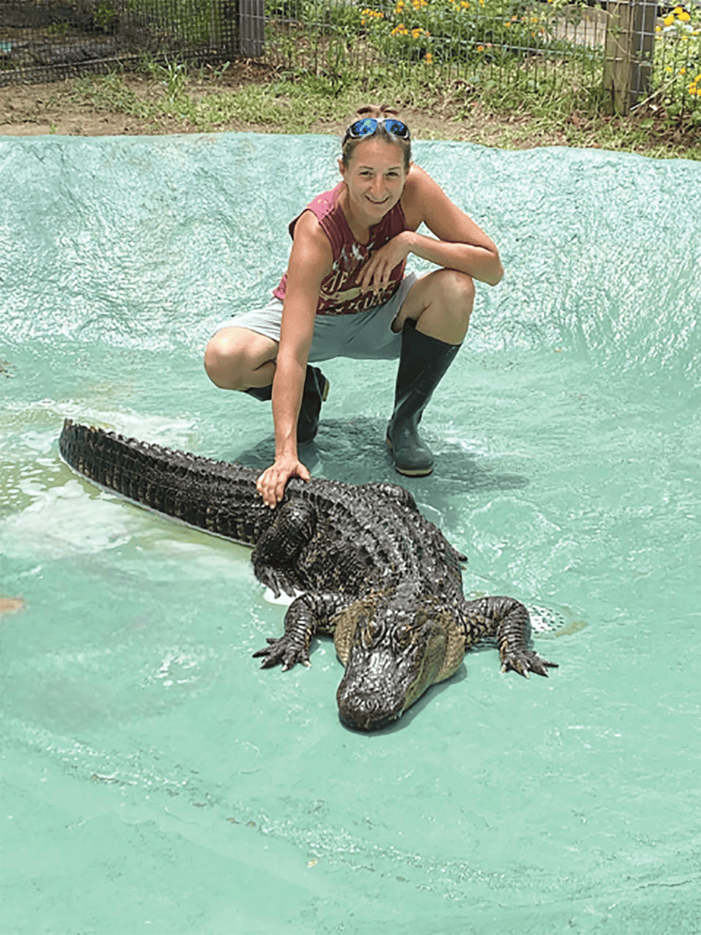 1. Woman with alligator at a wildlife sanctuary, outdoor setting.