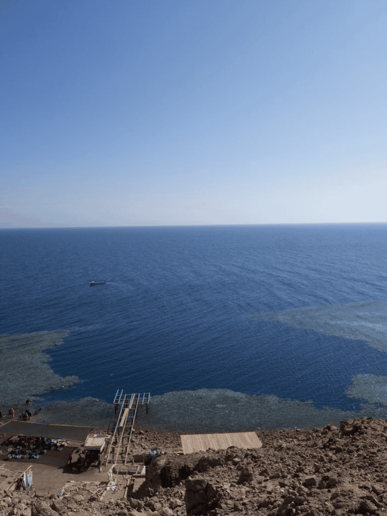 Breathtaking ocean view from coastal viewpoint, sunny sky, and rocky shoreline, perfect for travel and adventure.