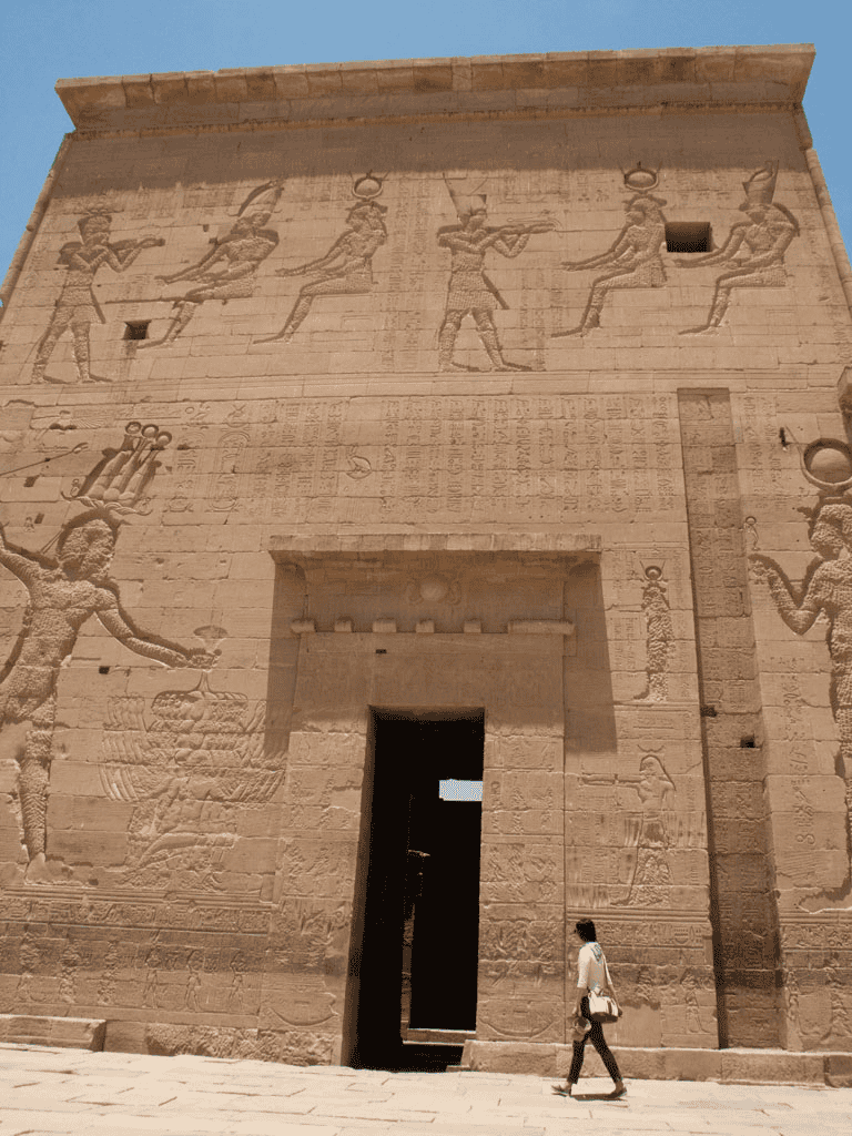 Ancient Egyptian temple wall with hieroglyphs and carvings, historical monument tour destination.