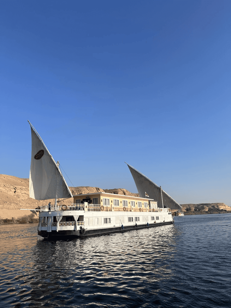 Elegant river cruise boat sailing on calm water with scenic desert landscape, perfect for travel exploration.