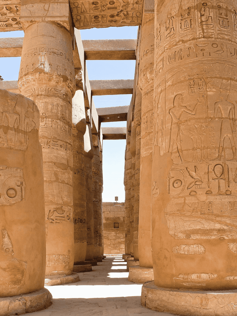Ancient Egyptian hieroglyphs on massive stone columns at Karnak Temple, Luxor.