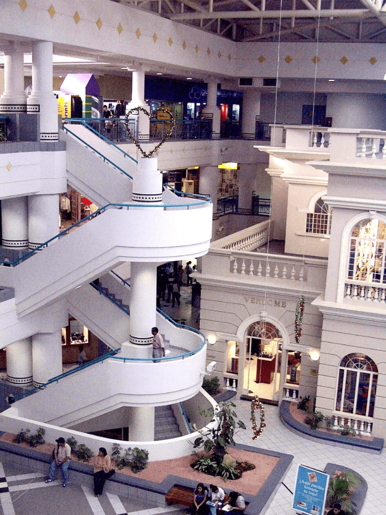 Bright indoor mall with elegant architecture and central spiral staircase, ideal for shopping and leisure.