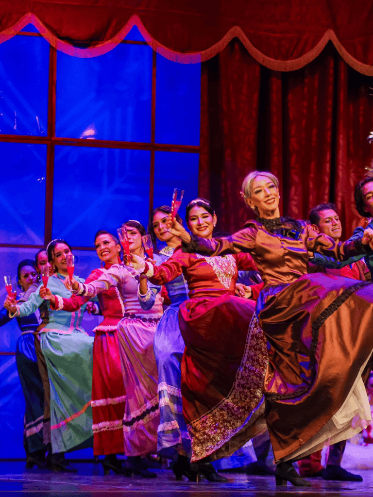 Elegant women in colorful vintage dresses performing on stage for the QuestForDirections theater experience.