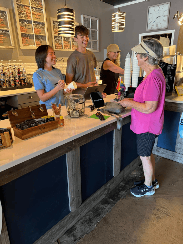 Fresh coffee being served at cozy cafe with smiling staff and happy customer enjoying a visit.