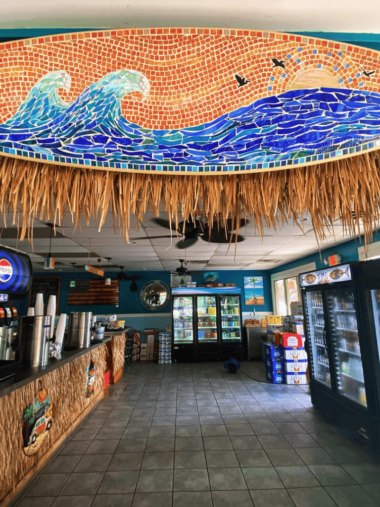 Wave mosaic mural with birds in a tropical restaurant interior.