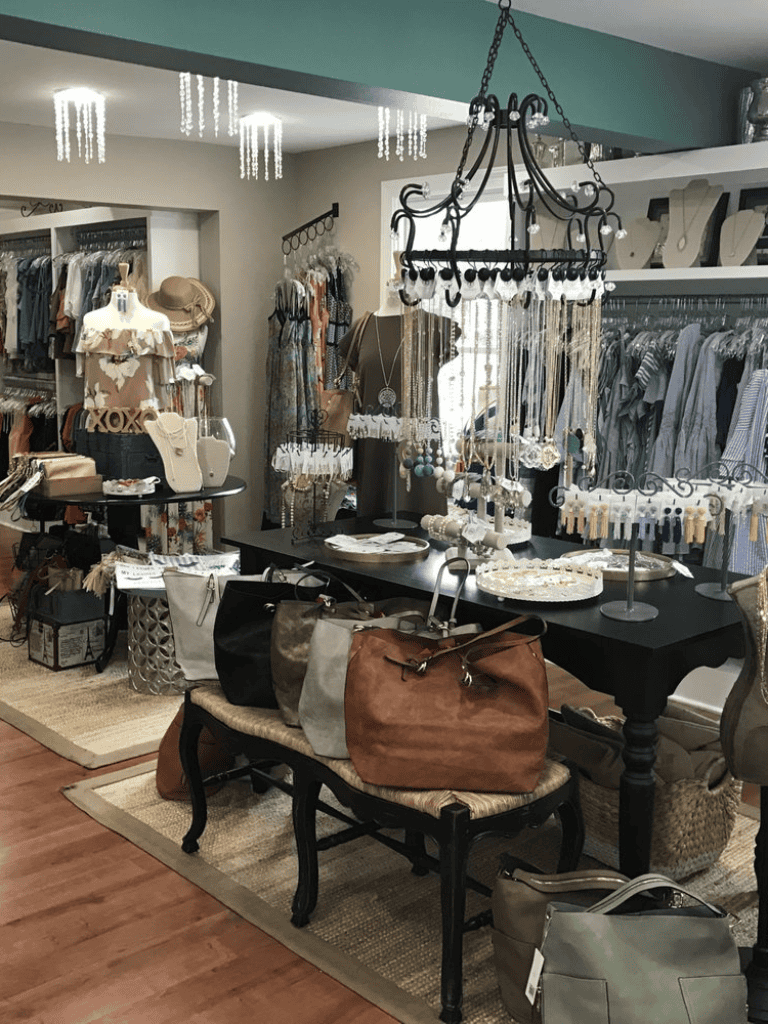 Chic boutique fashion accessories and handbags display with jewelry, decor, and clothing racks.