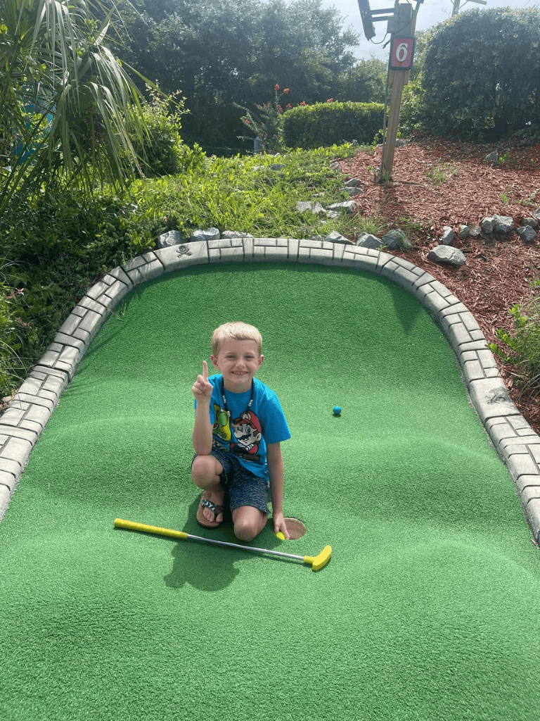 Miniature golf, child playing on putting green, outdoor mini golf course, kids fun activity, QuestForDirections.