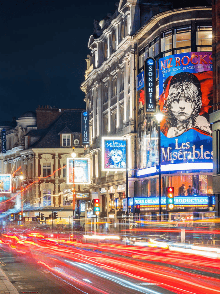 Bright city lights and colorful theater marquees in a vibrant urban night scene.