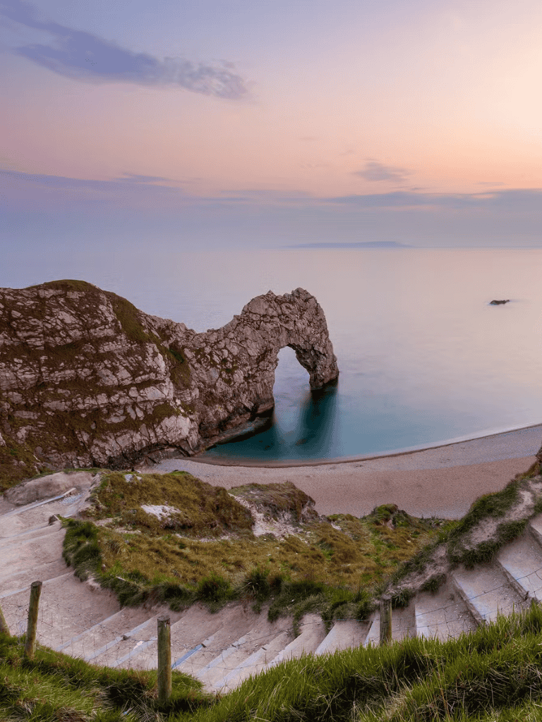 Elegant coastal landscape with natural rock arch at sunset, showcasing breathtaking seaside scenery.