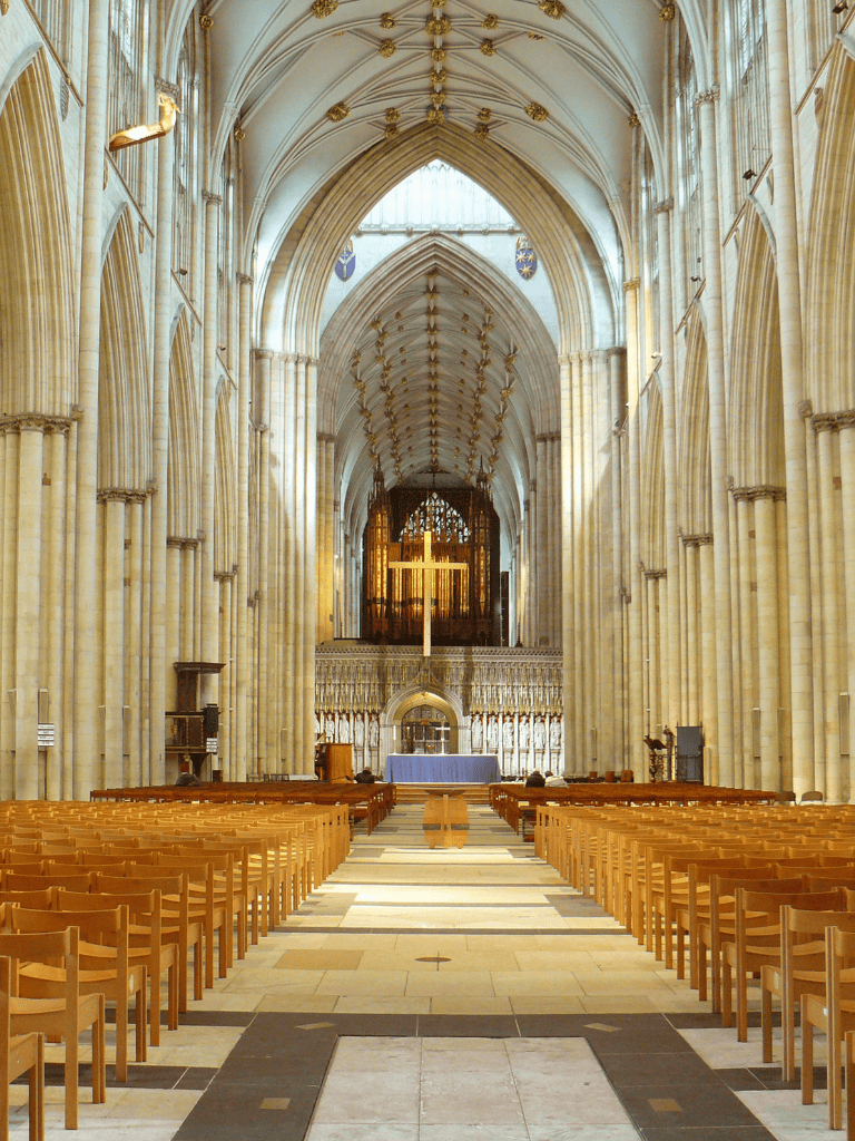 Ornate cathedral interior with high vaulted ceilings, wooden pews, and altar.