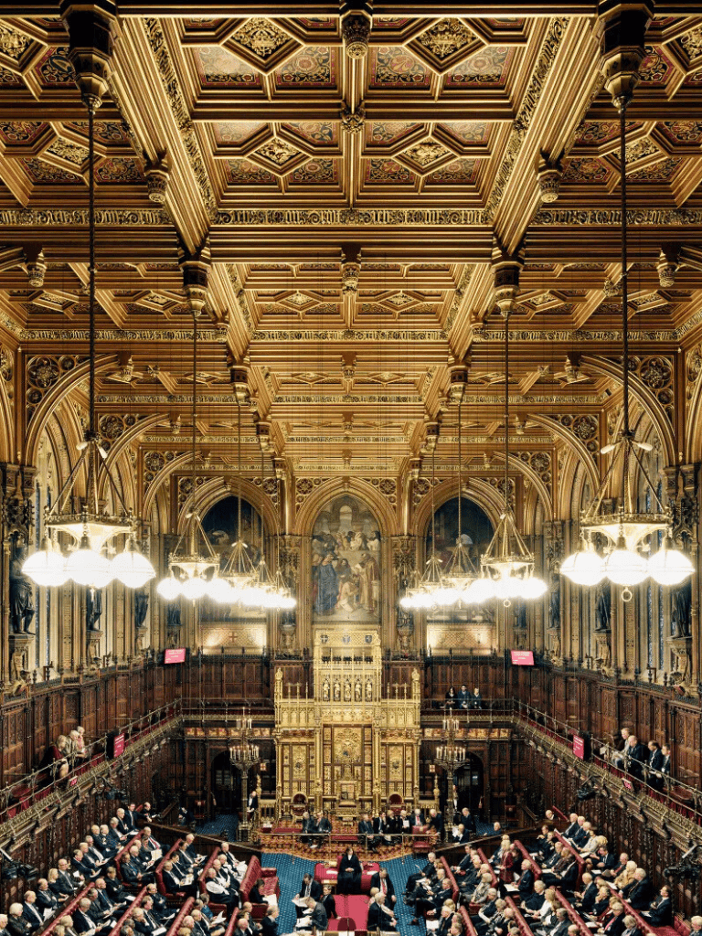 Luxurious historic parliament chamber with ornate wooden paneling and grand chandeliers.