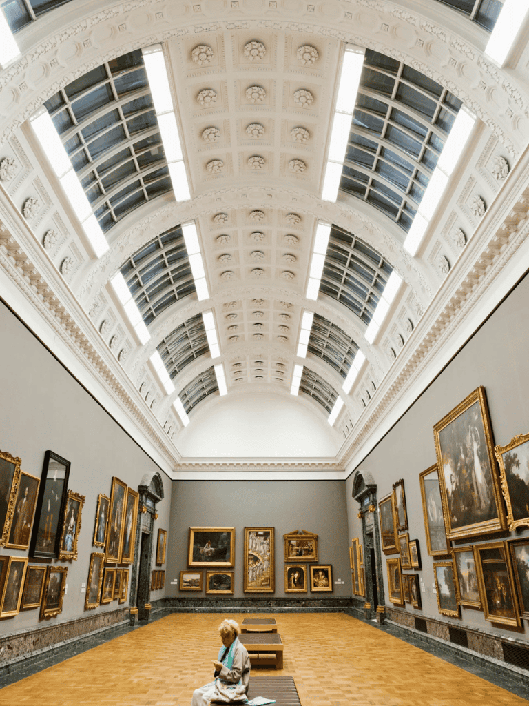 Arched historic museum interior with classic paintings and skylight ceiling, elegant and artistic ambiance.