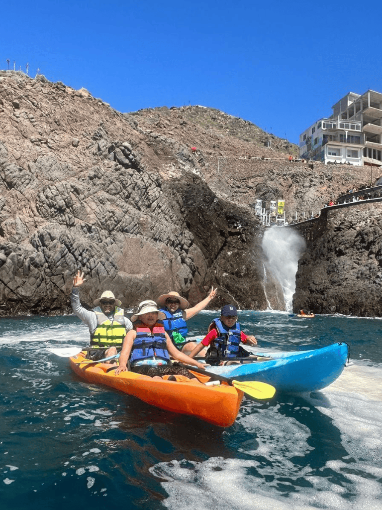 Exciting kayaking adventure with scenic coastal views and waterfall in the background.