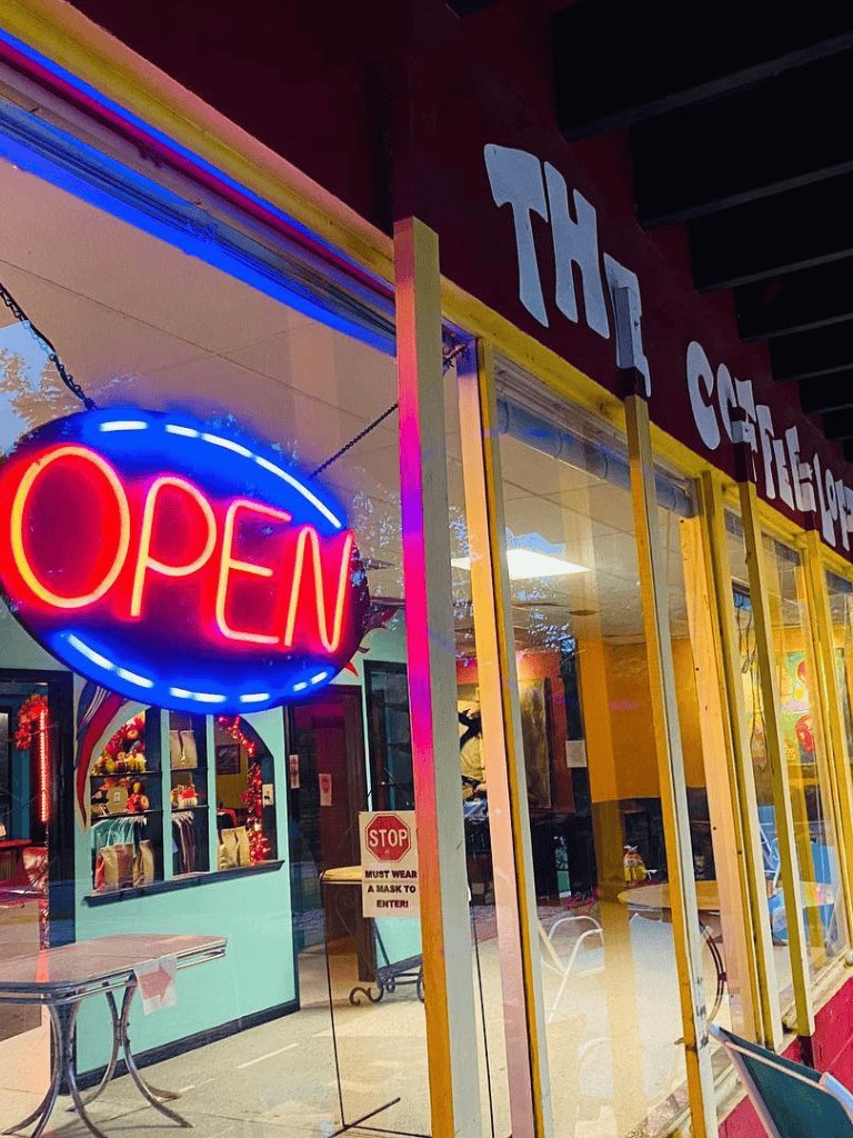 Open sign neon lights, storefront with colorful decor, inviting entry, quest for directions local guides.