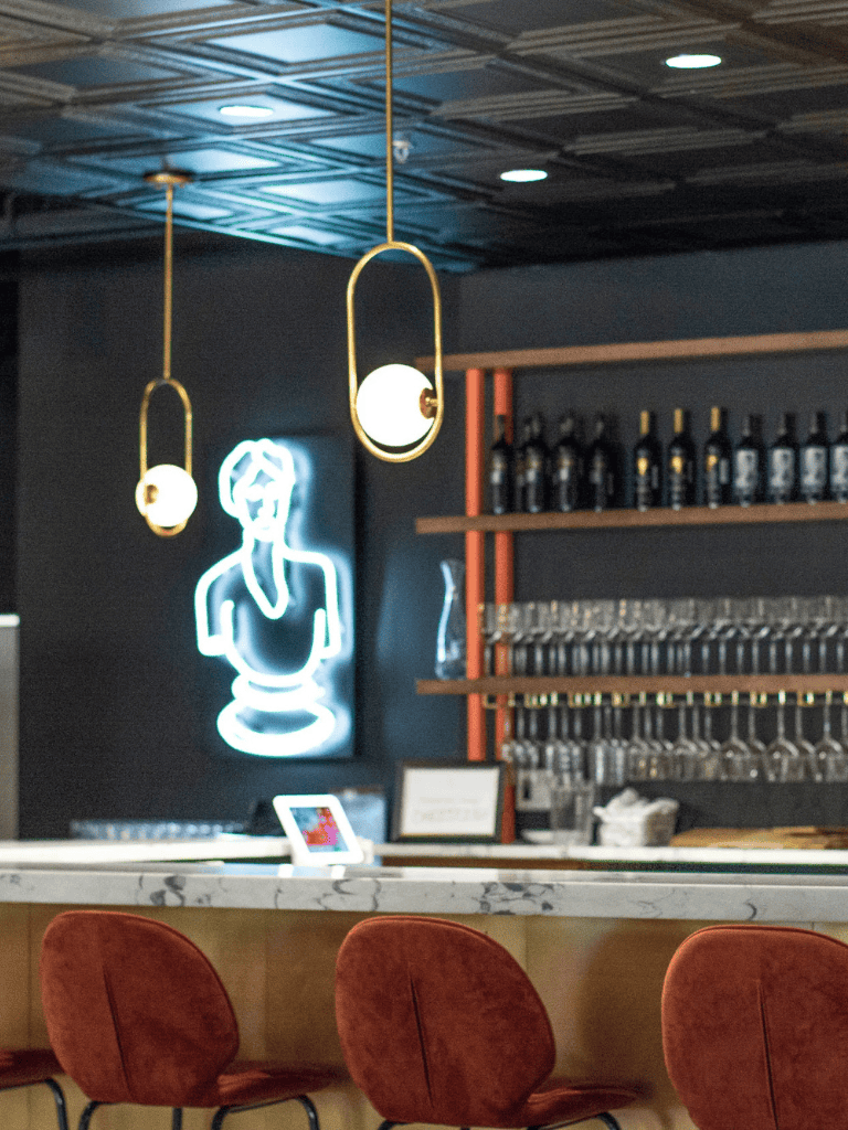 Neon woman silhouette art illuminating bar interior for modern, stylish restaurant ambiance.