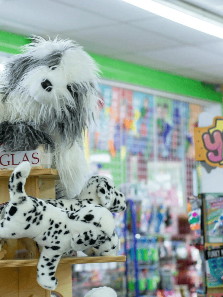 Colorful plush dog and panda toys on store display in QuestForDirections toy store.