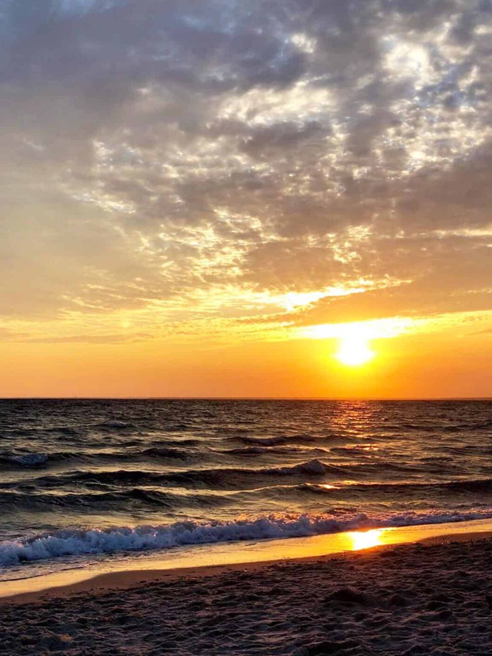Stunning beach sunset with vibrant colors and calm ocean waves.