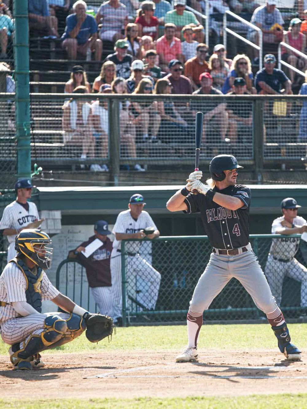 Youth baseball game at sunny stadium, players and audience enjoying an exciting match.