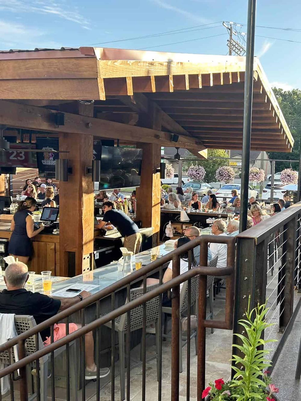 Outdoor restaurant with a lively crowd and wooden pergola, perfect for dining and socializing.