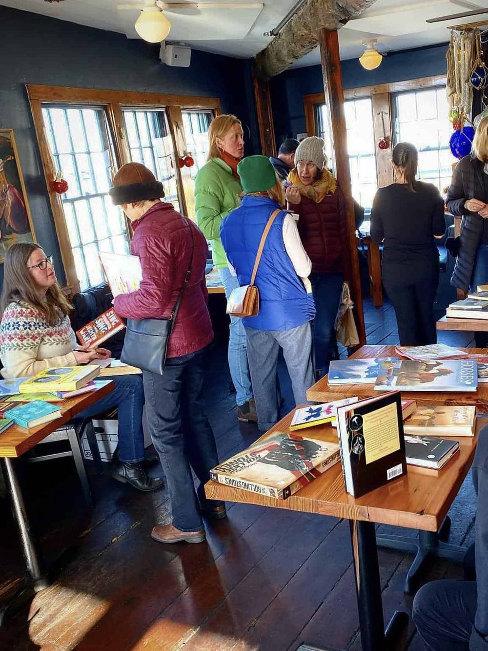Cozy bookshop with readers browsing and discussing books, creating a warm, inviting literary atmosphere.