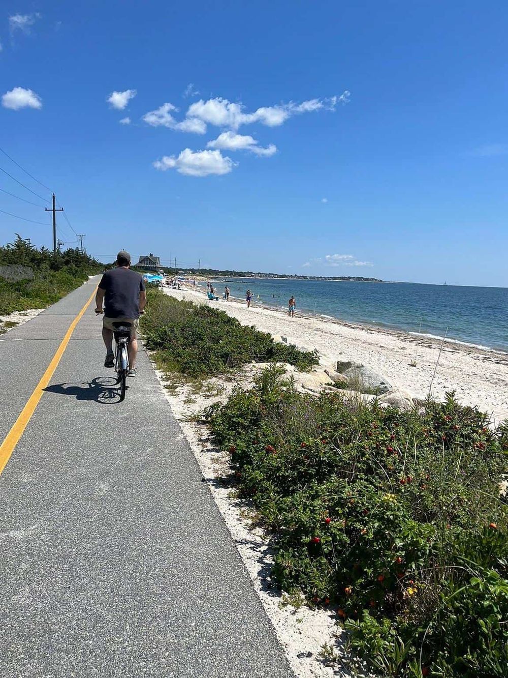 Scenic beach bike ride along coastal pathway with ocean views, sandy beach, and sunny weather.
