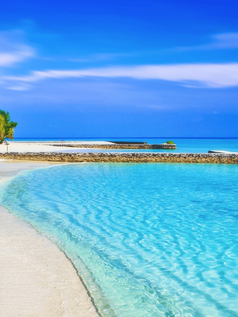 Serene tropical beach with clear turquoise waters and blue sky, perfect for relaxation and travel.