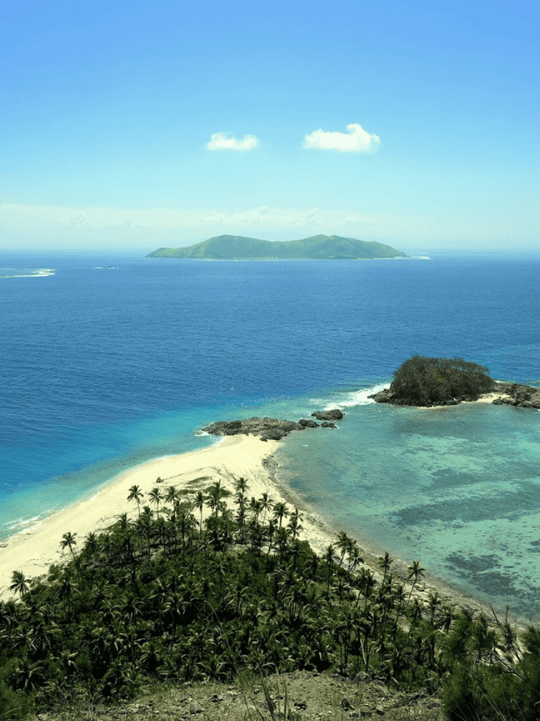 Breathtaking island view with lush greenery, clear blue waters, and tropical coastline.