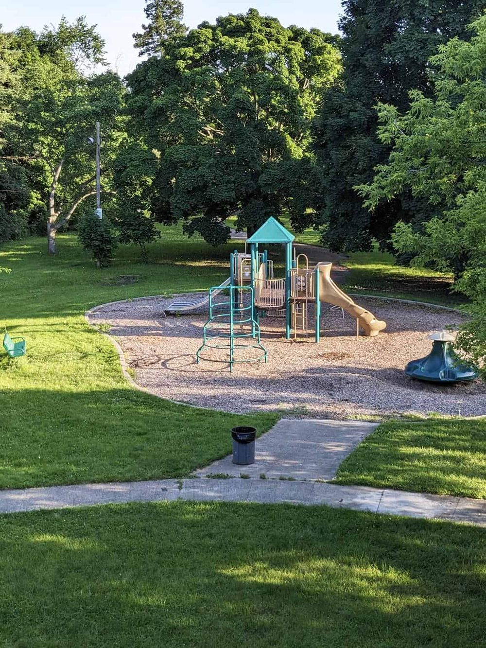 Bright outdoor playground with slides and climbing structures in a green park setting.