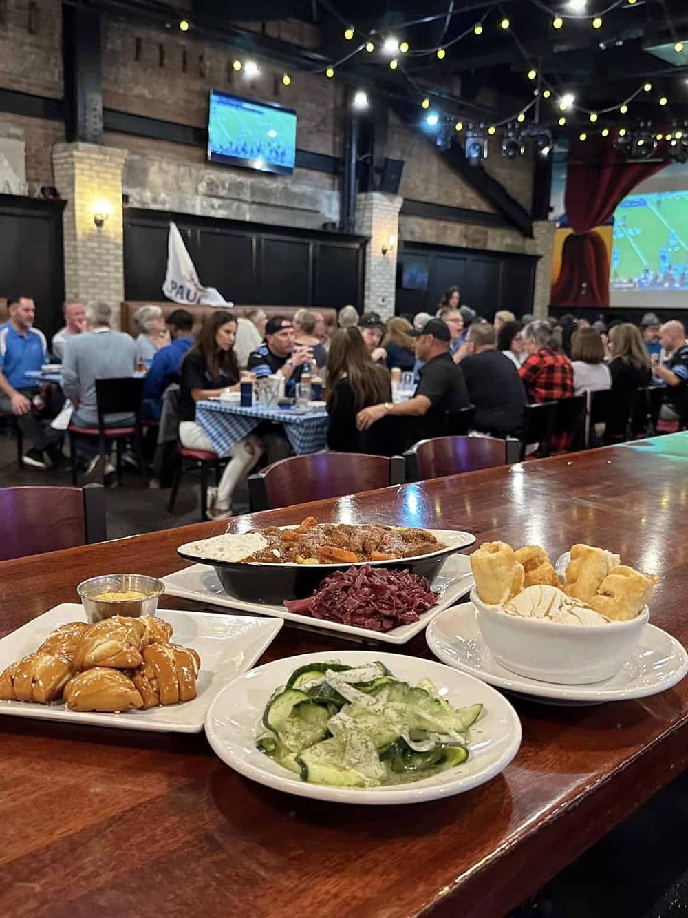 Delicious German-style dishes served at a lively sports bar with a large crowd watching a game.