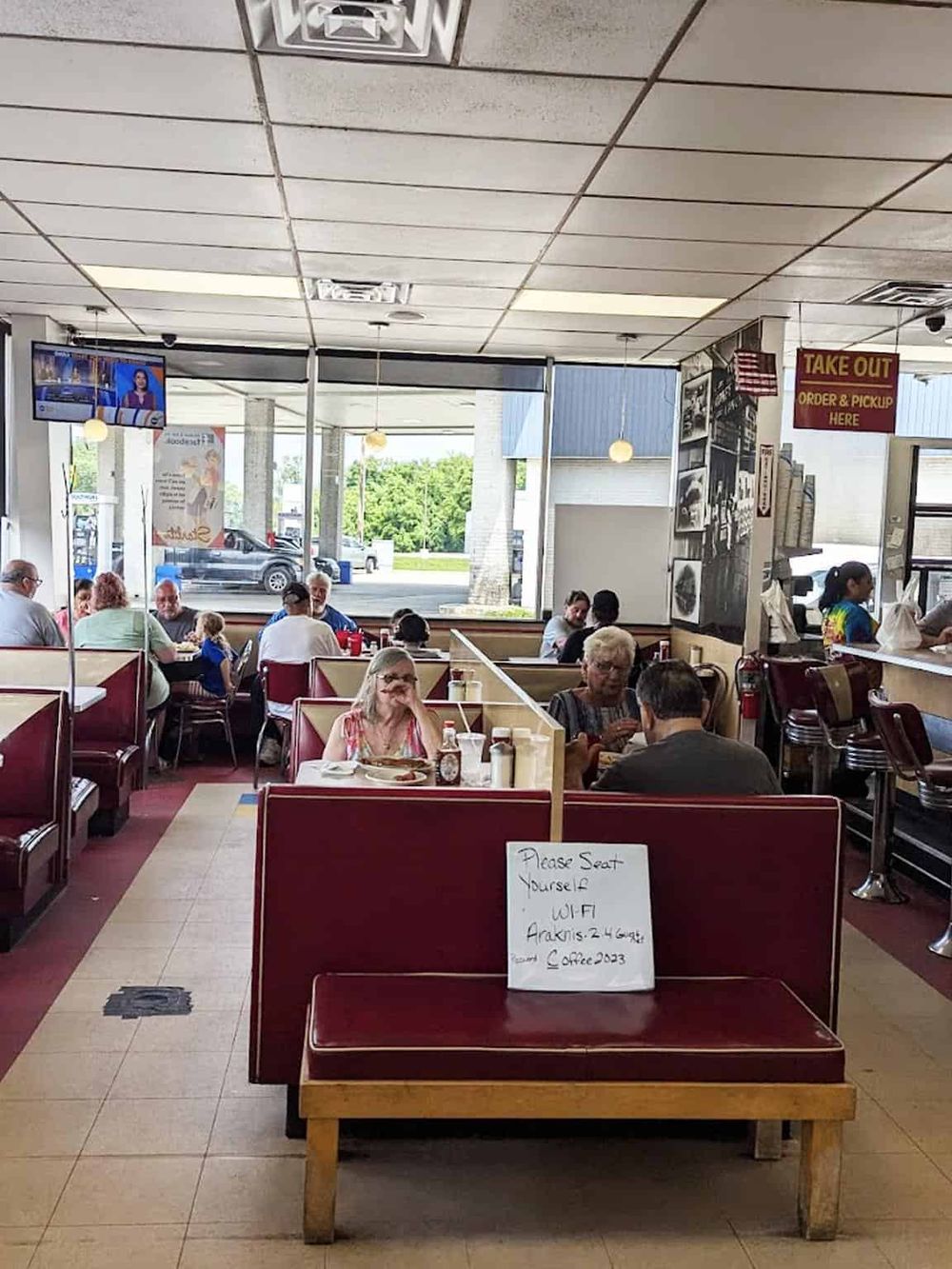 A crowded indoor dining restaurant with customers enjoying their meals and a sign indicating WiFi availability.