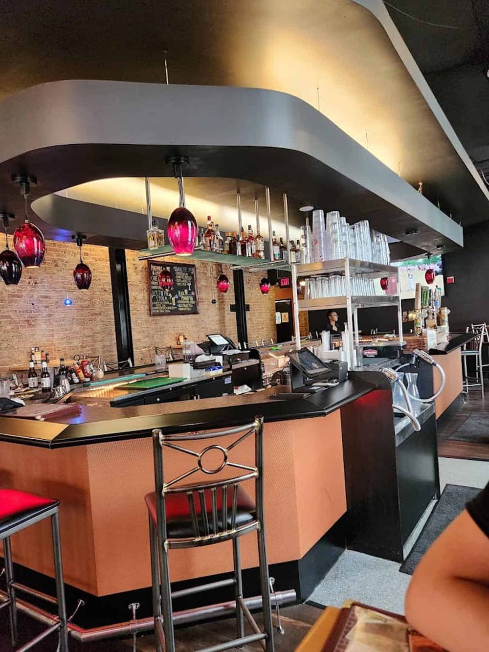 Modern bar with colorful pendant lights and inviting seating area, perfect for socializing and drinks.