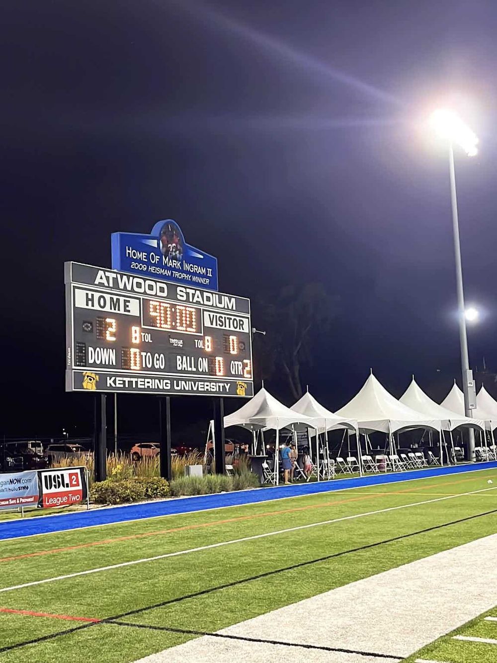 Scoreboard at Atwood Stadium during night game, showcasing sports scores and lighting.