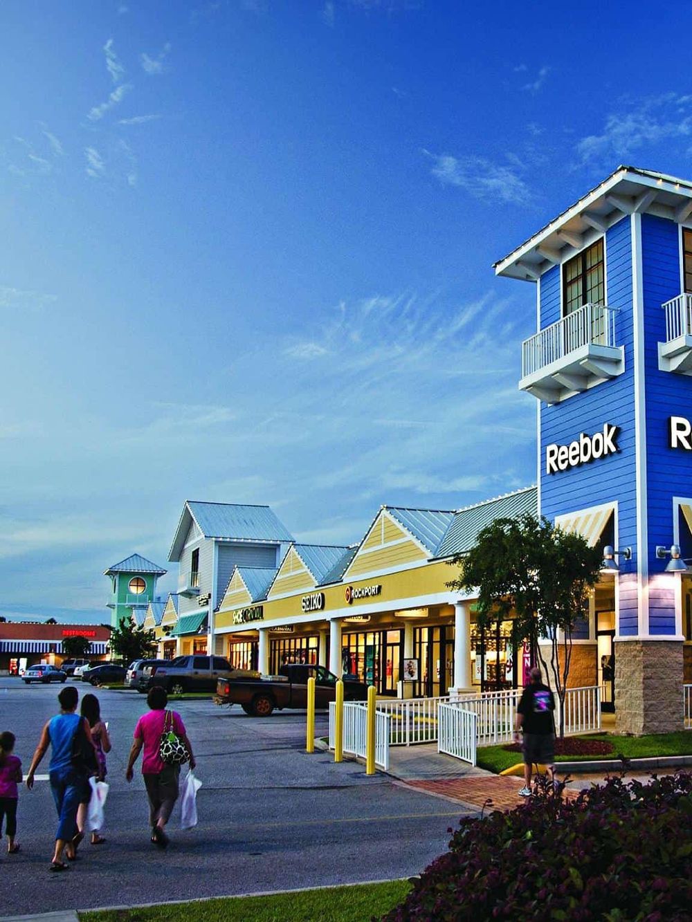 Bright shopping mall exterior with colorful storefronts and people walking, showcasing QuestForDirections retail solutions.