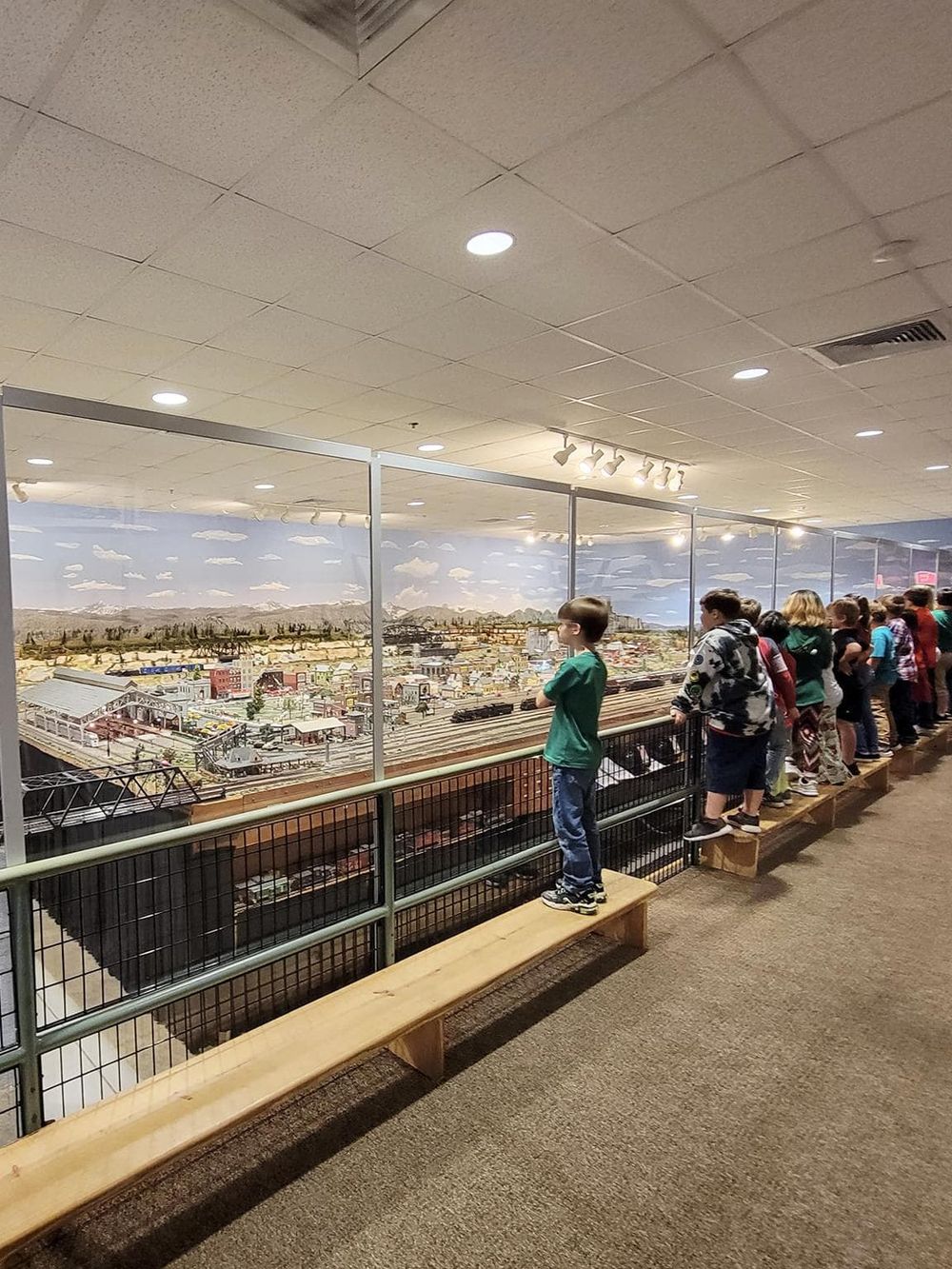 Children observing a detailed model train layout at QuestForDirections exhibit.