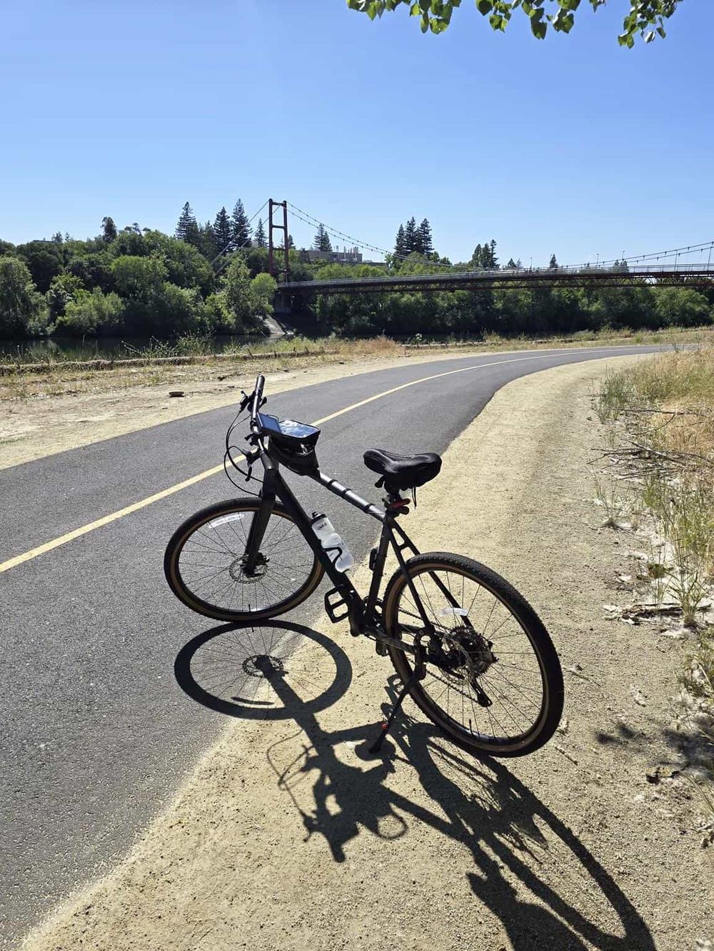 Scenic bike trail near a bridge with lush greenery and clear blue sky, perfect for outdoor adventure and exploration.