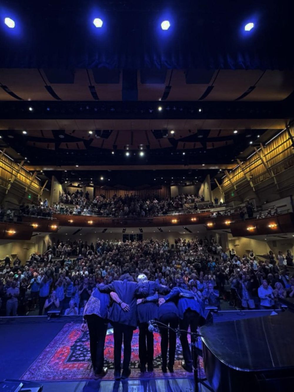 People gathering on stage at a theater or concert hall during an event or performance.