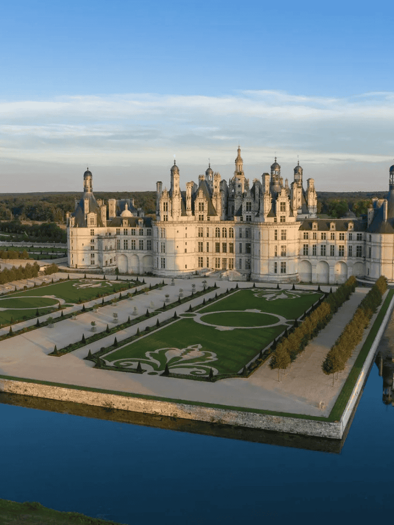 Elegant European castle with manicured gardens and reflective moat, ideal for destination wedding venues.