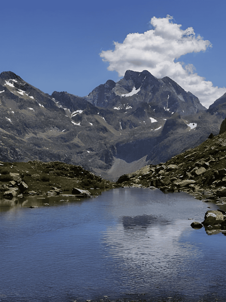 Serene mountain lake with snow-capped peaks and blue sky in the background.