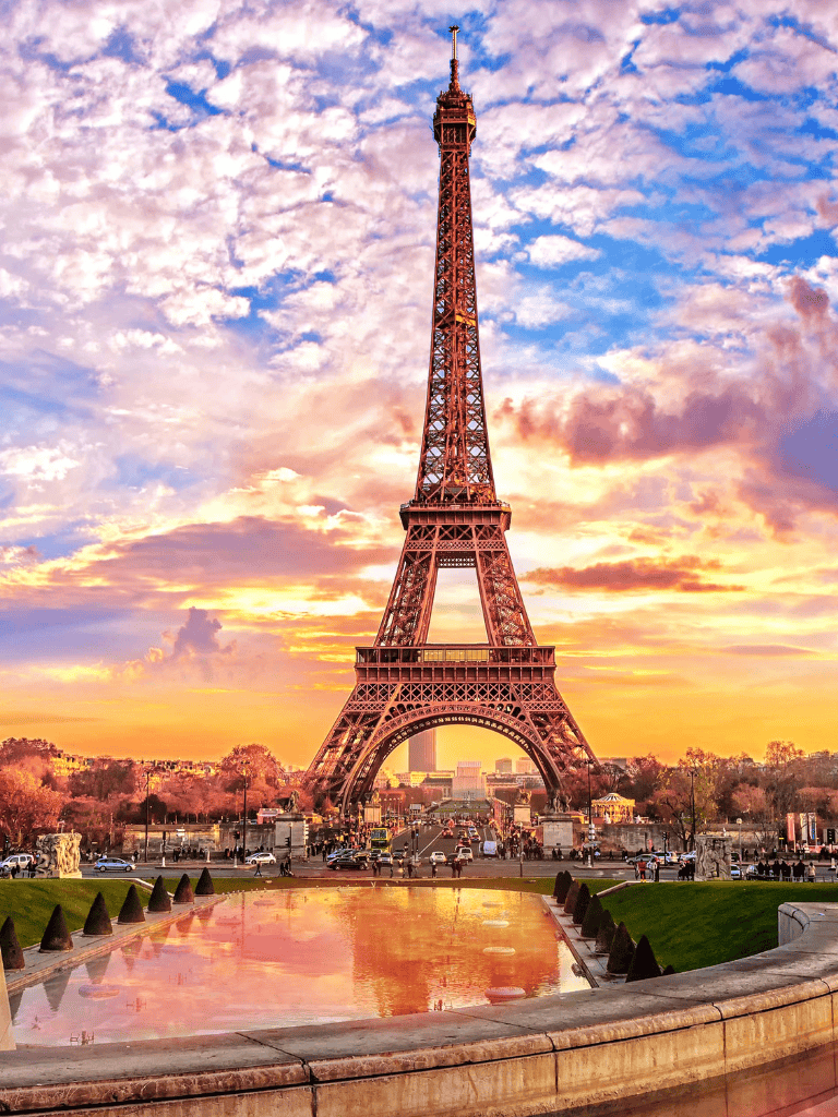 Eiffel Tower at sunset with colorful sky and reflections in water.
