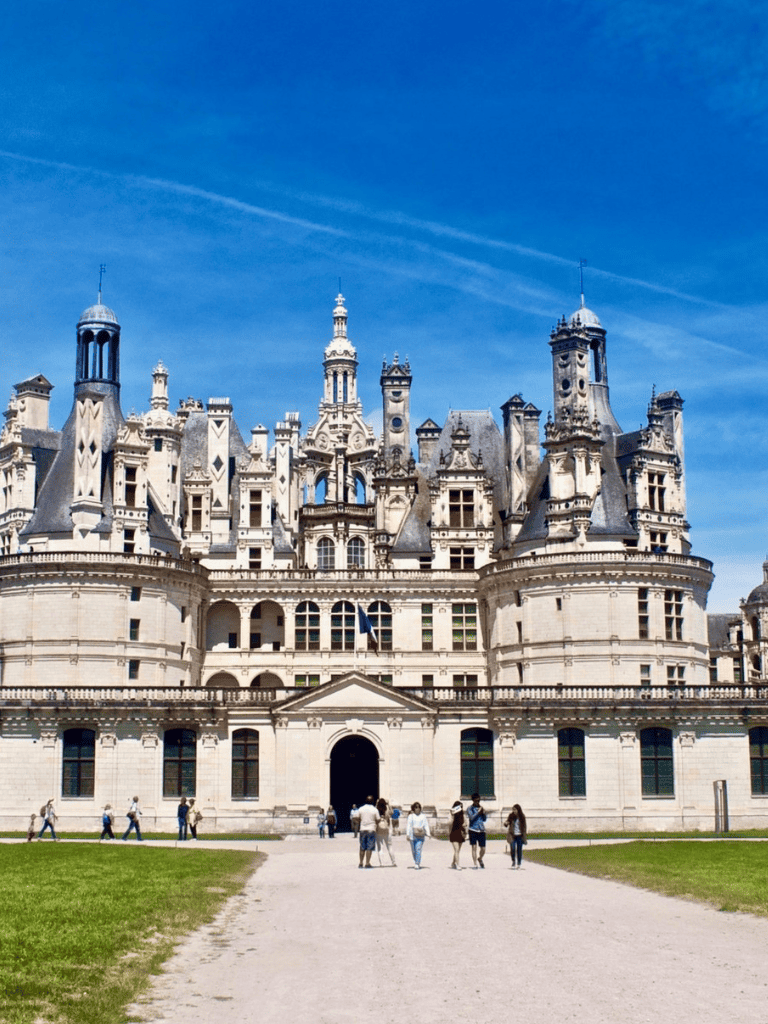 Majestic castle with ornate architecture and tall towers under a bright blue sky.