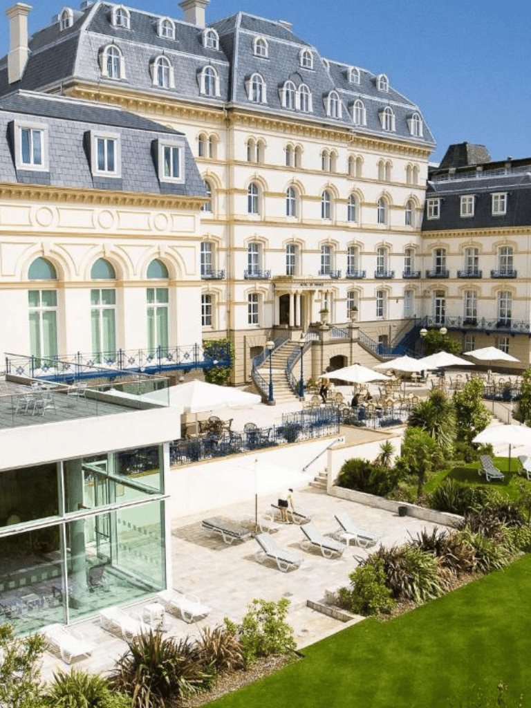 Luxurious hotel with classic architecture and outdoor terrace, perfect for travel planning and directions.