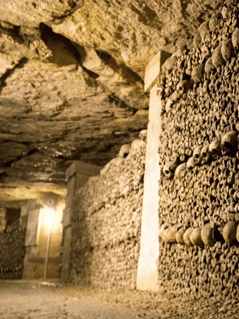 Ancient catacombs with skull stacks and dim lighting, exploring history and mysteries.