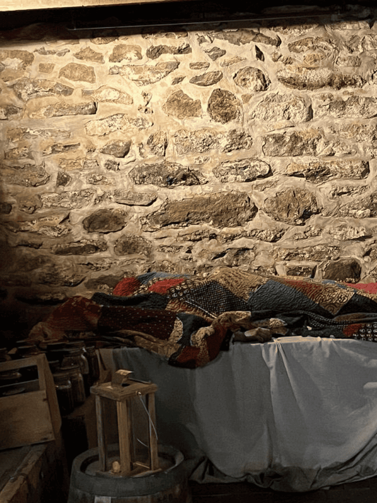 Rug-covered table against rustic stone wall, cozy vintage ambiance, authentic historic interior decor Quests for directions.