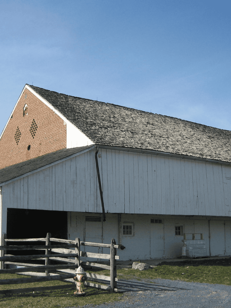1. Rustic barn with wooden fencing under clear blue sky, rural landscape.