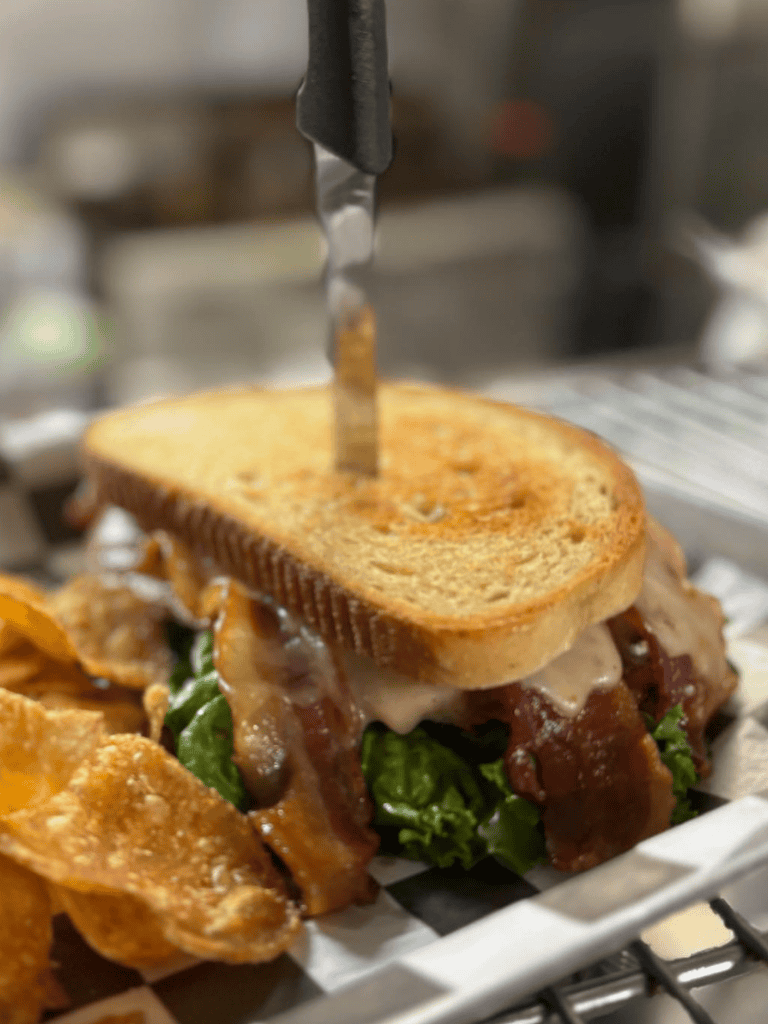 Crispy bacon grilled cheese sandwich with potato chips, close-upshot, delicious comfort food.