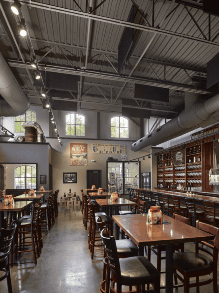 Indoor brewery taproom with high ceilings, large windows, and rustic wooden furnishings.
