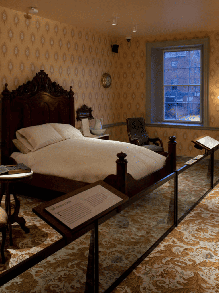 Antique bedroom with vintage furniture and patterned wallpaper.