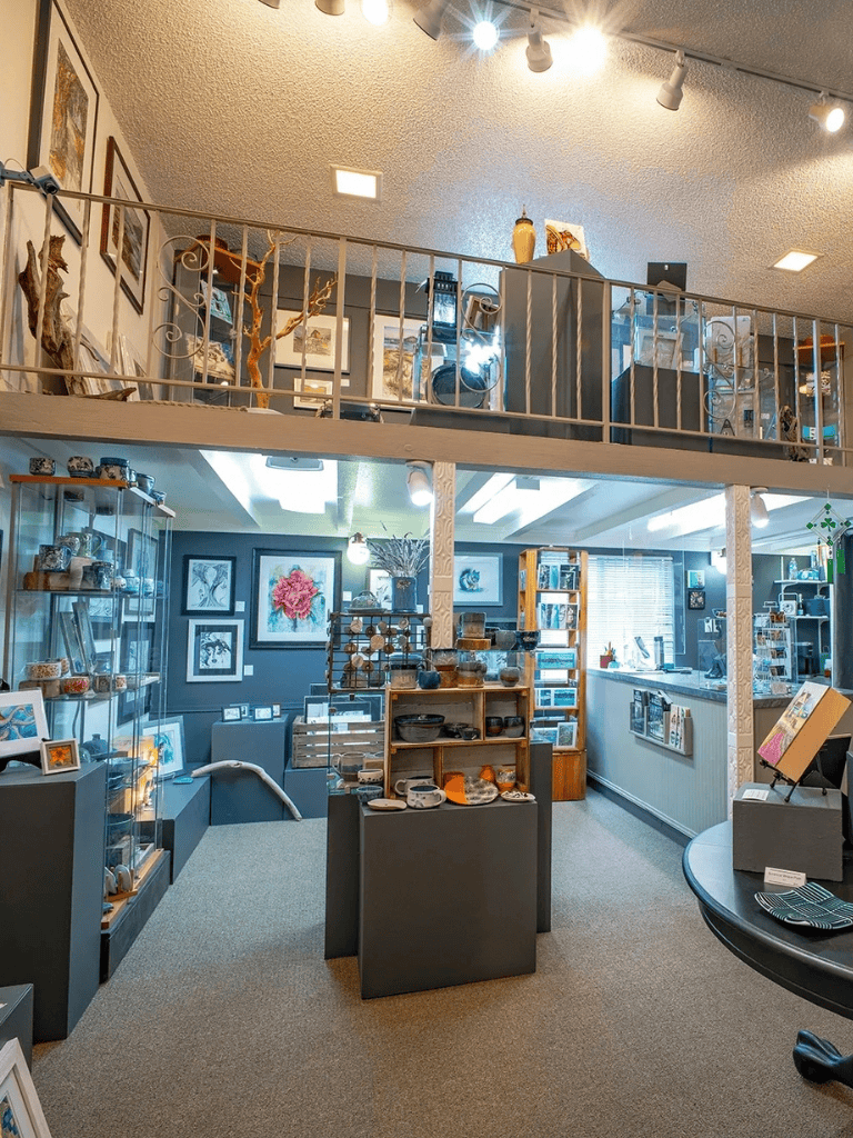 Aesthetic art store with pottery, paintings, and sculptures displayed on shelves and walls.